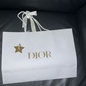 White Dior shopping bag with gold star shaped bag charm.